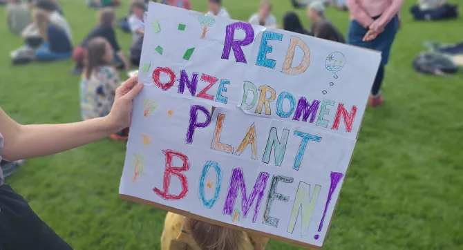 bord van kind bij klimaatprotest met tekst 'Red onze dromen, plant bomen'