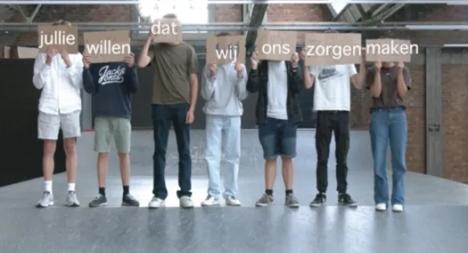 7 jongeren met bordjes die samen de zin 'jullie willen dat wij ons zorgen maken' vormen