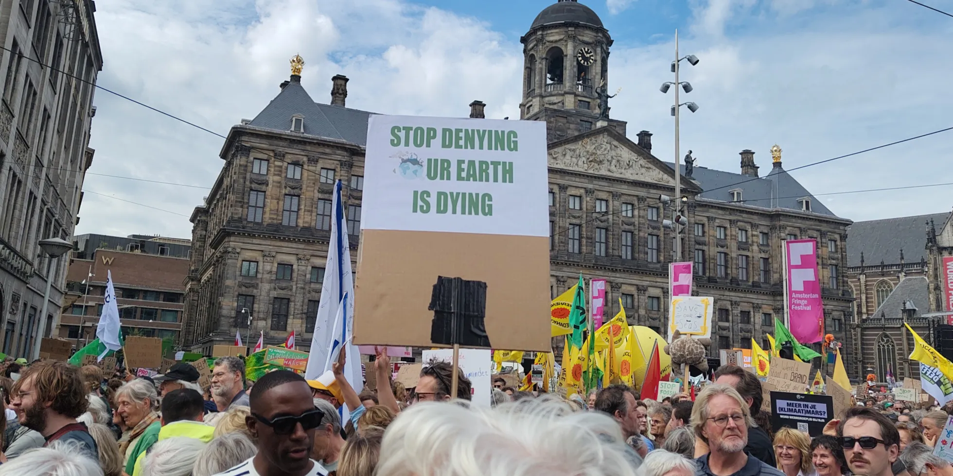 klimaatdemonstratie in Amsterdam met bord 'Stop denying our earth is dying'